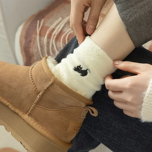 Detail of warm fluffy socks with cat embroidery and cozy sherpa lining on boots