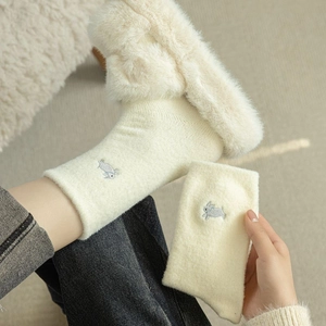 Detail of warm fluffy socks with cute rabbit embroidery and thick coral fleece texture