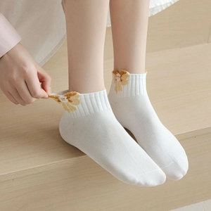 Detail of white knit socks with yellow floral embroidery and elastic ribbed cuff