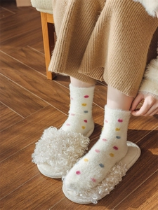 Detail of warm white fuzzy mid-calf socks with colorful polka dots and plush texture