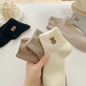 Gros plan de chaussettes en coton côtelé avec broderie ours mignon en couleurs neutres