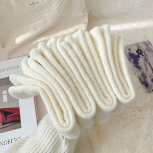 Close-up of thick beige fuzzy socks showing soft plush texture and warm ribbed cuffs