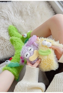 Close-up of fuzzy monster socks with 3D eyes and soft plush texture in vibrant colors