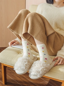 Detail of warm white fuzzy teddy fleece slippers paired with colorful polka dot socks