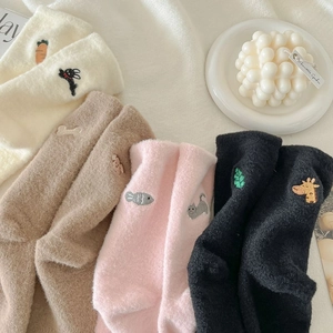 Detail of four pairs of warm plush socks featuring cute animal embroidery in soft colors