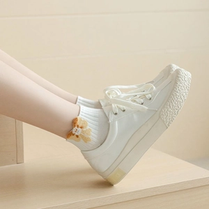 Close-up of white crew socks with plush feather yarn and brown floral embroidery detail