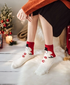 Detail of Christmas snowman coral fleece socks with 3D red pom-poms in a cozy home setting