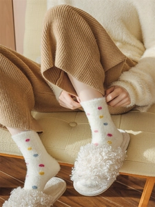 Detail of warm white fuzzy socks with colorful dots and plush slippers for winter