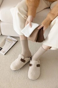 Close-up of thick winter cotton socks and plush slippers in warm earth tones