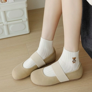 Détail de chaussettes en coton côtelé blanc avec broderie ours et chaussures Mary Jane beige