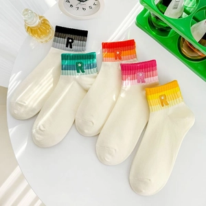 Detail view of five pairs of combed cotton socks with letter R embroidery on a table
