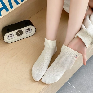 Detail of white mesh breathable ankle sock with cute colorful embroidery on a wooden table
