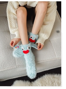 Detail of fuzzy light blue monster sleep socks with 3D eyes and soft plush texture