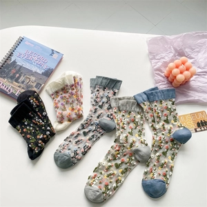 Detail of floral embroidered sheer glass silk socks in various colors on a white desk