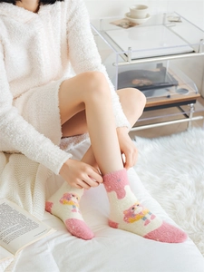 Detail of warm pink fuzzy socks with cute cartoon design on soft white carpet