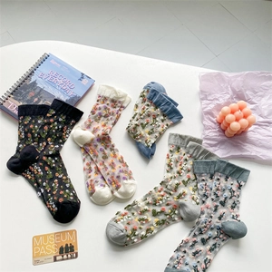 Flat lay of five floral embroidered sheer crew socks in various colors on a white desk