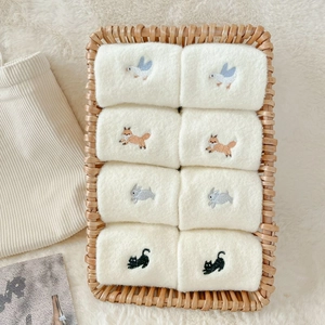 Set of 8 white coral fleece warm socks with cute animal embroidery in a wicker basket