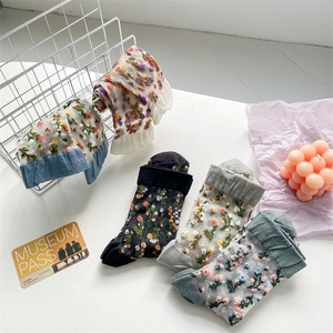 Detail of floral sheer mesh crew socks with elegant ruffled cuffs in various colors