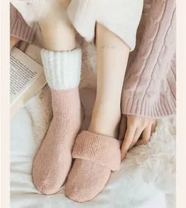Gros plan de chaussettes thermiques en laine rose avec revers en peluche sur tapis blanc