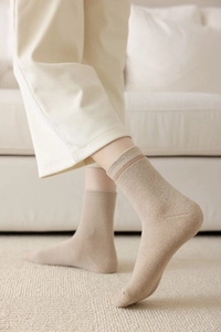 Close-up of thick knitted oatmeal wool crew socks with ribbed cuffs on model