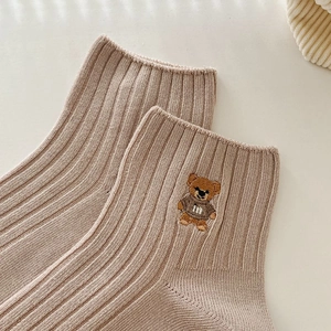 Gros plan sur chaussette en coton côtelé avoine avec broderie ours et détail de la lettre m
