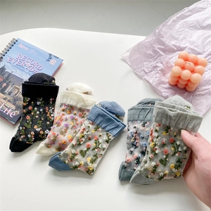 Detail view of sheer floral embroidery on four pairs of pastel tulle mid-calf socks