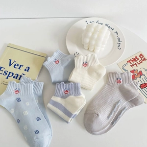 Detailed shot of blue and white cotton socks with cute cartoon face embroidery and frills