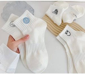 Detail of white cotton crew socks with colorful cartoon embroidery and ribbed cuffs