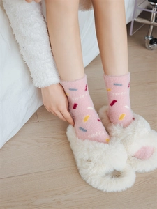 Close-up of pink fluffy winter socks with SWEET embroidery and colorful accents