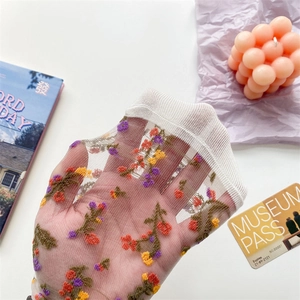 Detail of white transparent tulle socks with colorful floral embroidery for women