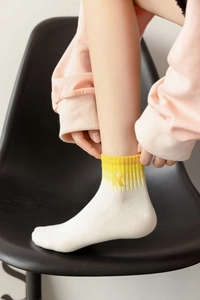 Close-up of white cotton sock featuring a yellow R letter embroidery and star detail