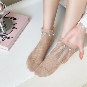 Detailed close-up of beige mesh lace socks with white pearl embellishment on the cuff