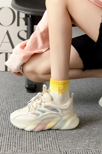 Detail of chunky sneakers with gradient soles and cotton socks featuring embroidered R letter