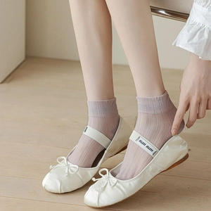 Detail of light purple striped socks paired with white satin ballet flats and bows