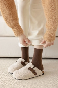 Detail of warm off-white fleece mule slippers with dark brown leather buckle strap