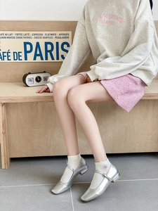 Close-up of white wavy edge socks with silver Mary Jane shoes and pink tweed skirt