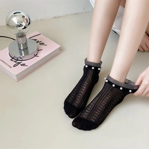 Close-up of black mesh lace socks with white pearl trim and delicate knit texture