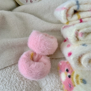 Close-up of soft pink faux mink fur scrunchies with plush winter socks on knit background