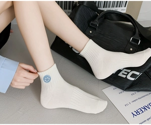 Detail of white cotton crew socks with a blue smiling face embroidery on the ankle