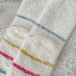 Macro detail of soft white mink velvet socks with vibrant colorful horizontal stripes
