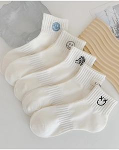 Detailed view of white cotton crew socks with diverse embroidered smiley face patterns
