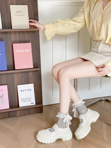 Détail de chaussettes grises à dentelle avec chaussures Mary Jane blanches à plateforme