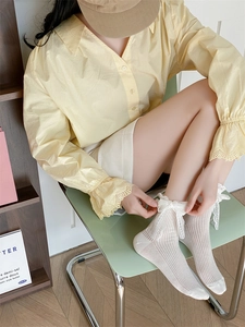 Détail de chaussettes lolita blanches avec bordure en dentelle et nœud en soie