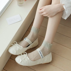 Close-up of cream soft leather ballet flats with bow detail and logo elastic strap