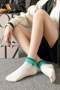 Detail of white cotton ankle socks with green gradient stripes and embroidered R letter