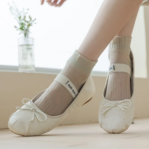 Detail of off-white ballet flats with bow and elastic logo strap on ribbed socks