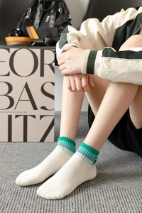 Detail of white cotton ankle sock featuring colorful striped cuff and embroidered star logo