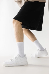 Gros plan de chaussettes blanches côtelées avec baskets en cuir blanches et short noir