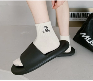 Close-up of a white knitted mid-tube sock featuring a black cartoon bear embroidery