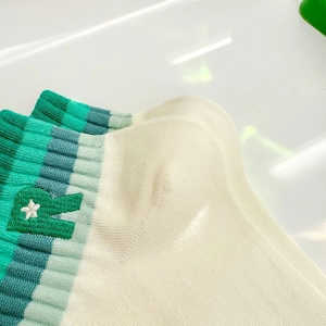 Macro detail of ribbed cotton sock cuff with green letter R and star embroidery